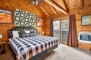 Ein Schlafzimmer in einer Blockhütte mit Bett, Decke, gerahmten Bildern und einem Heizgerät.