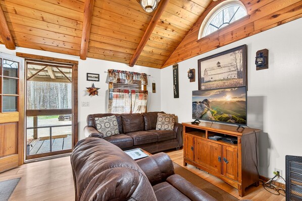 A cozy living room with a leather sofa, wooden entertainment center, and a large TV.