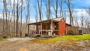 Un chalet rustique doté d’une véranda, d’une terrasse en bois et d’une cour clôturée.