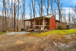 A rustic cabin with a porch, a wooden deck, and a fenced yard. - Lazy Lane Cabins - Lazy Lane (South Bloomingville)