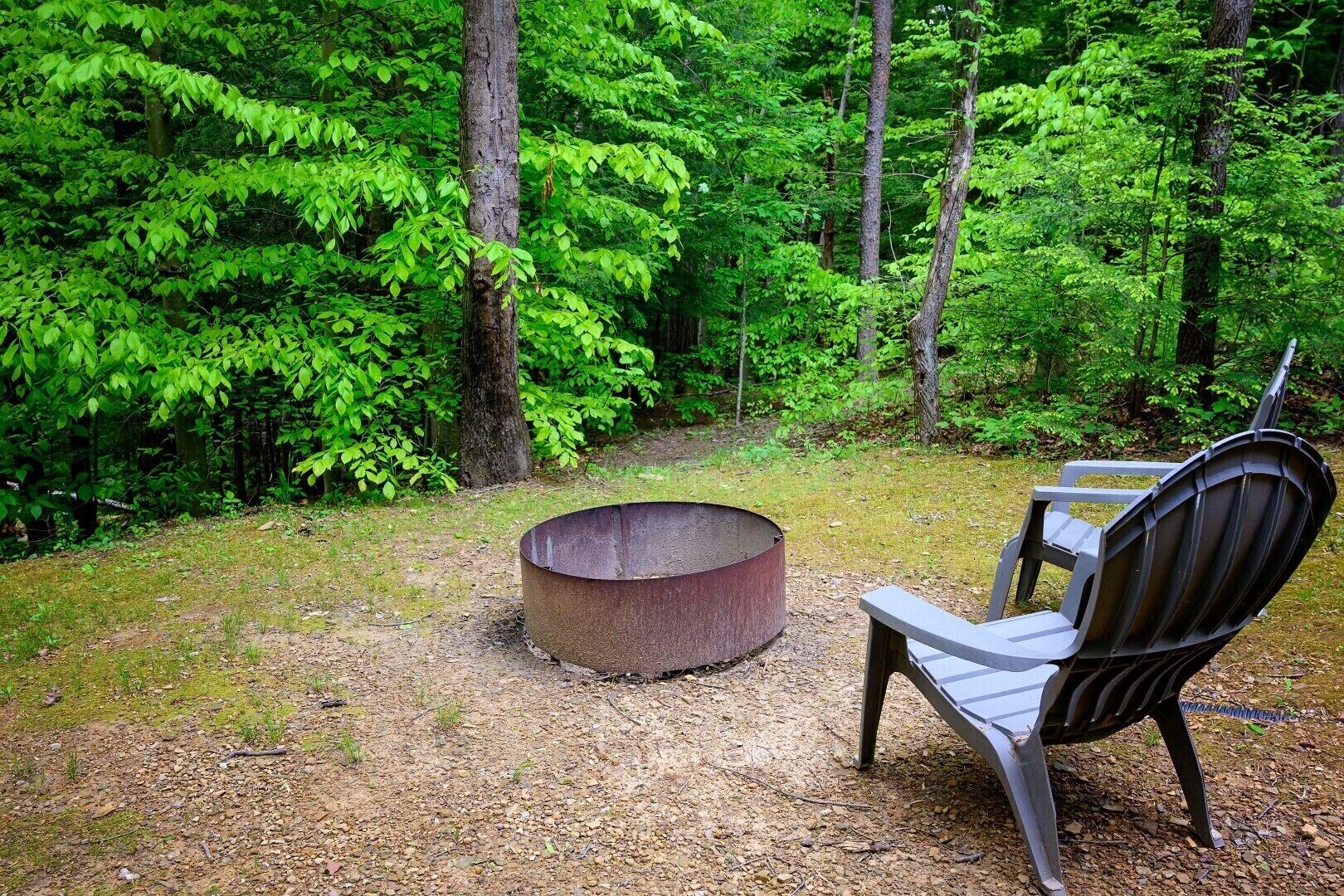 Un terrain de camping équipé d’un foyer en métal et d’une chaise en métal.