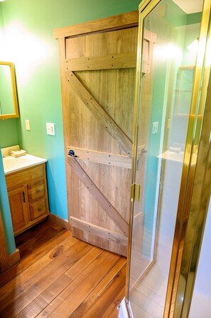A bathroom with a wooden door, a sink, and a mirror.