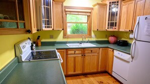 Une cuisine avec des meubles de rangement en bois, un évier, une cuisinière et un réfrigérateur.