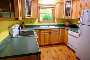 A kitchen with wooden cabinets, a sink, a stove, and a refrigerator.