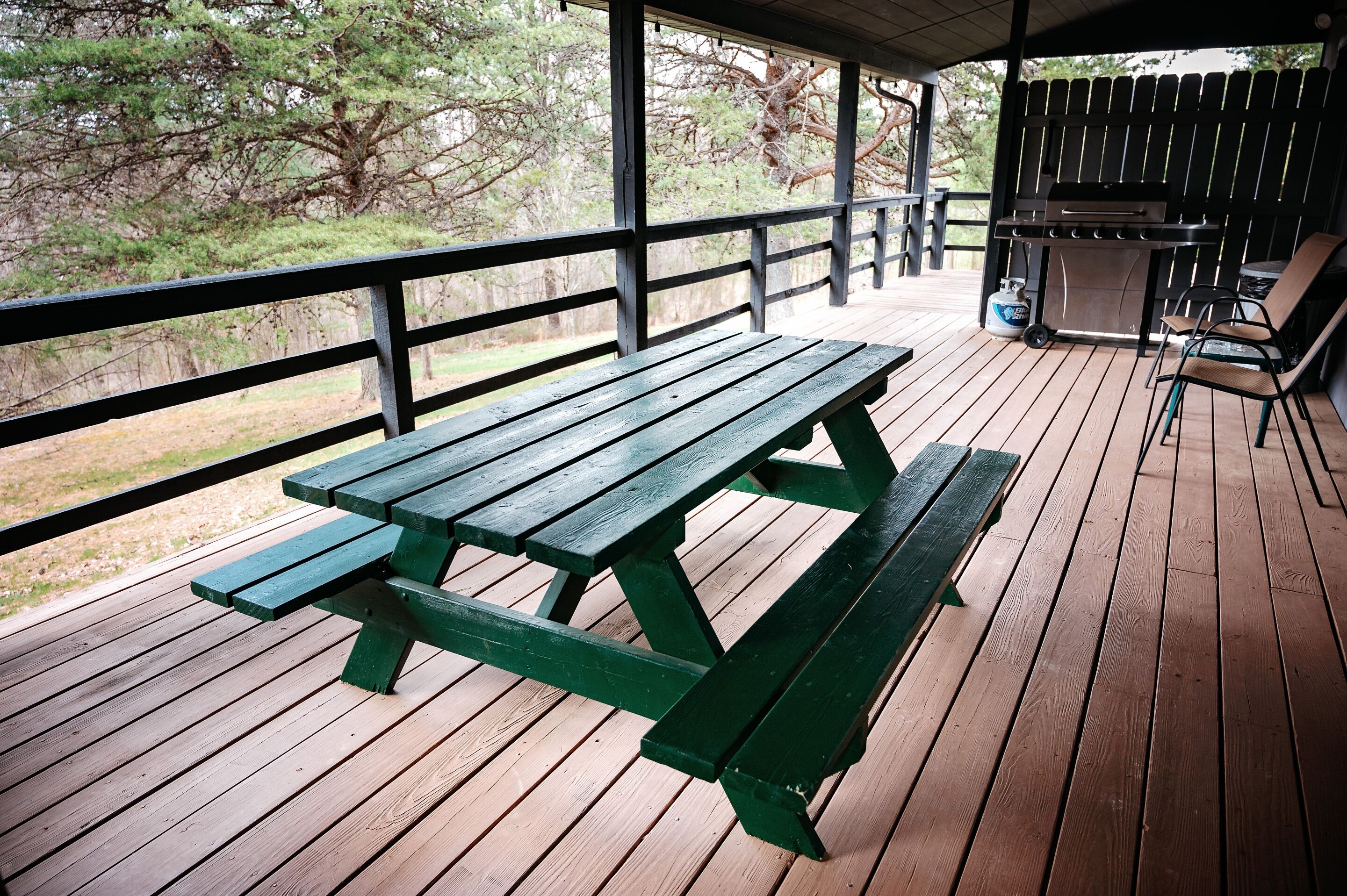 Eine Holzterrasse mit Picknicktisch und Grill.