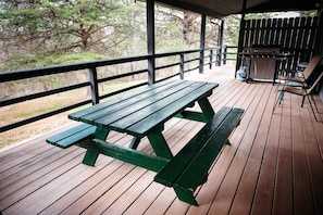A wooden deck with a picnic table and a barbecue grill. - Lazy Lane Cabins - Blue Jay (South Bloomingville)