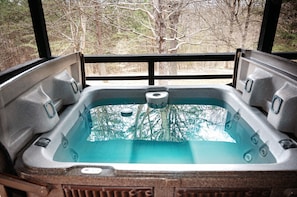 A hot tub with a view of trees through a black railing. - Lazy Lane Cabins - Blue Jay (South Bloomingville)