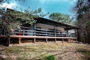 Ein Holzhaus mit überdachter Terrasse und einem umzäunten Bereich.