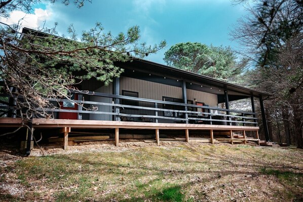 A wooden building with a covered deck and a fenced area.