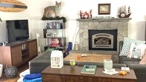 A living room with a fireplace, a sofa, a coffee table, and a bookshelf. - Updated Mid-Century beach house --10 minute walk to the beach (Carlsbad)