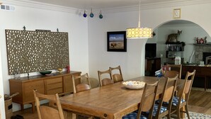 A dining area with a wooden table and chairs, a patterned rug, and a decorative wall panel. - Updated Mid-Century beach house --10 minute walk to the beach (Carlsbad)