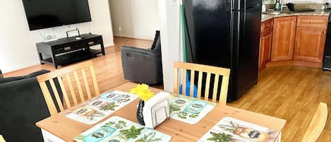Una cocina moderna con armarios de madera, un refrigerador negro y una mesa de comedor con camino de mesa floral.