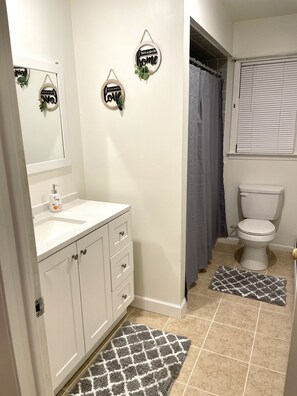 Een bad/douchecombinatie, een haardroger, handdoeken, zeep