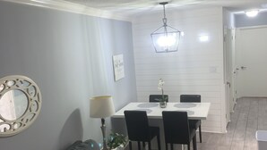 A modern living room with a grey sofa, a dining table with chairs, a chandelier, and a white door in the background.