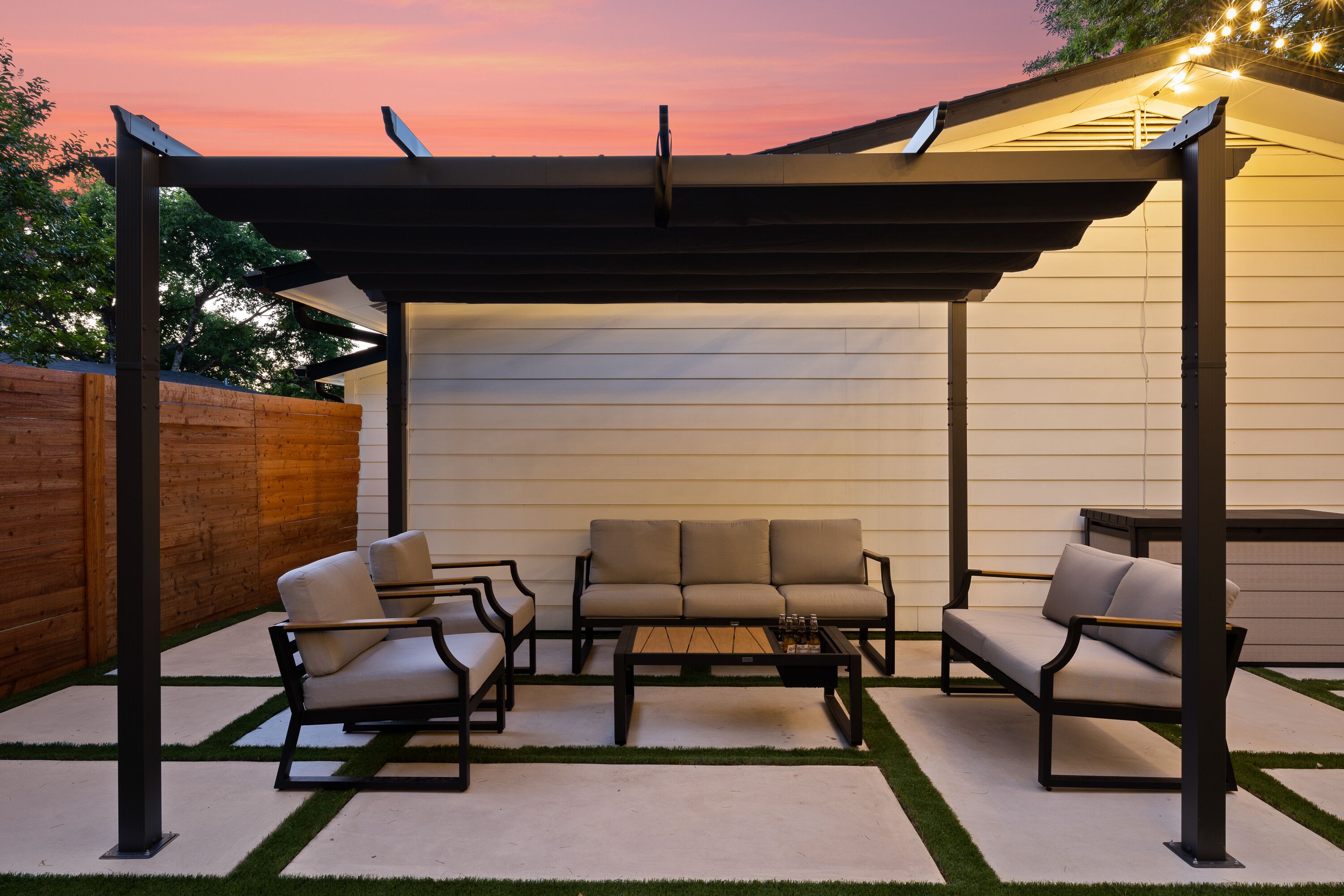 An outdoor patio with a pergola, a sofa set, and a coffee table.