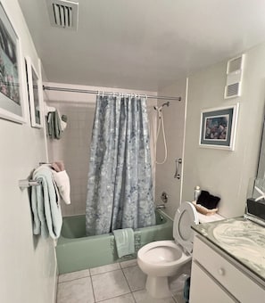 Een badkamer met een bad, toilet en douchegordijn.