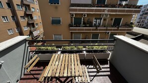 A balcony with a wooden table and chairs, surrounded by potted plants and a tiled floor. - Carpegna House. Lovely apartment: Rome (Roma)
