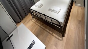 A neatly made bed with white linens, a bedside table, and a nightstand with a lamp. - Carpegna House. Lovely apartment: Rome (Roma)