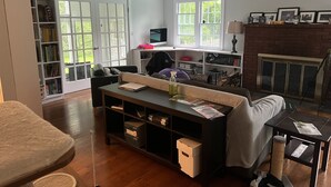 Una sala de estar con sofá, mesa de centro, estantería, chimenea y televisor.