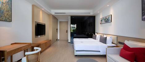 A modern hotel room with a bed, a sofa, a desk, and a TV.