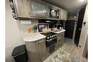 Kitchen features a central island with a range, microwave, and ample storage.