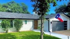 Une maison de plain-pied avec un garage, un petit jardin devant et un drapeau du Texas.