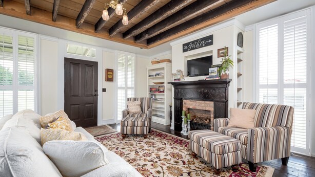 A living room with a sofa, striped armchairs, a fireplace, and a decorative rug. - Charming 1-bedroom Pearl Cottage with WiFi in the historic Casey Jones Village (Jackson)