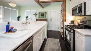 A kitchen with white cabinets, a stainless steel stove, and a large island with a sink. - Charming 1-bedroom Pearl Cottage with WiFi in the historic Casey Jones Village (Jackson)
