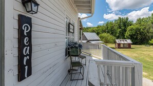 A white wooden house with a porch, a sign reading "Pearl", and a small red shed in the background. - Charming 1-bedroom Pearl Cottage with WiFi in the historic Casey Jones Village (Jackson)