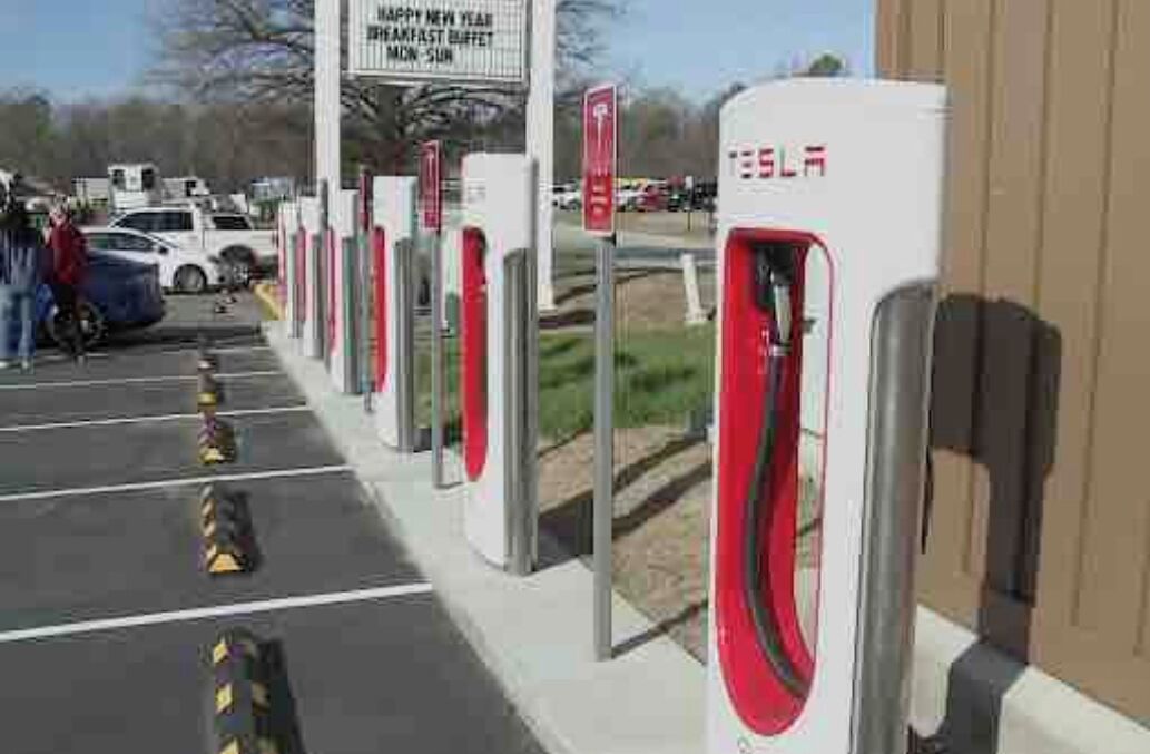 A parking lot with electric vehicle charging stations, a signboard, and a building in the background.