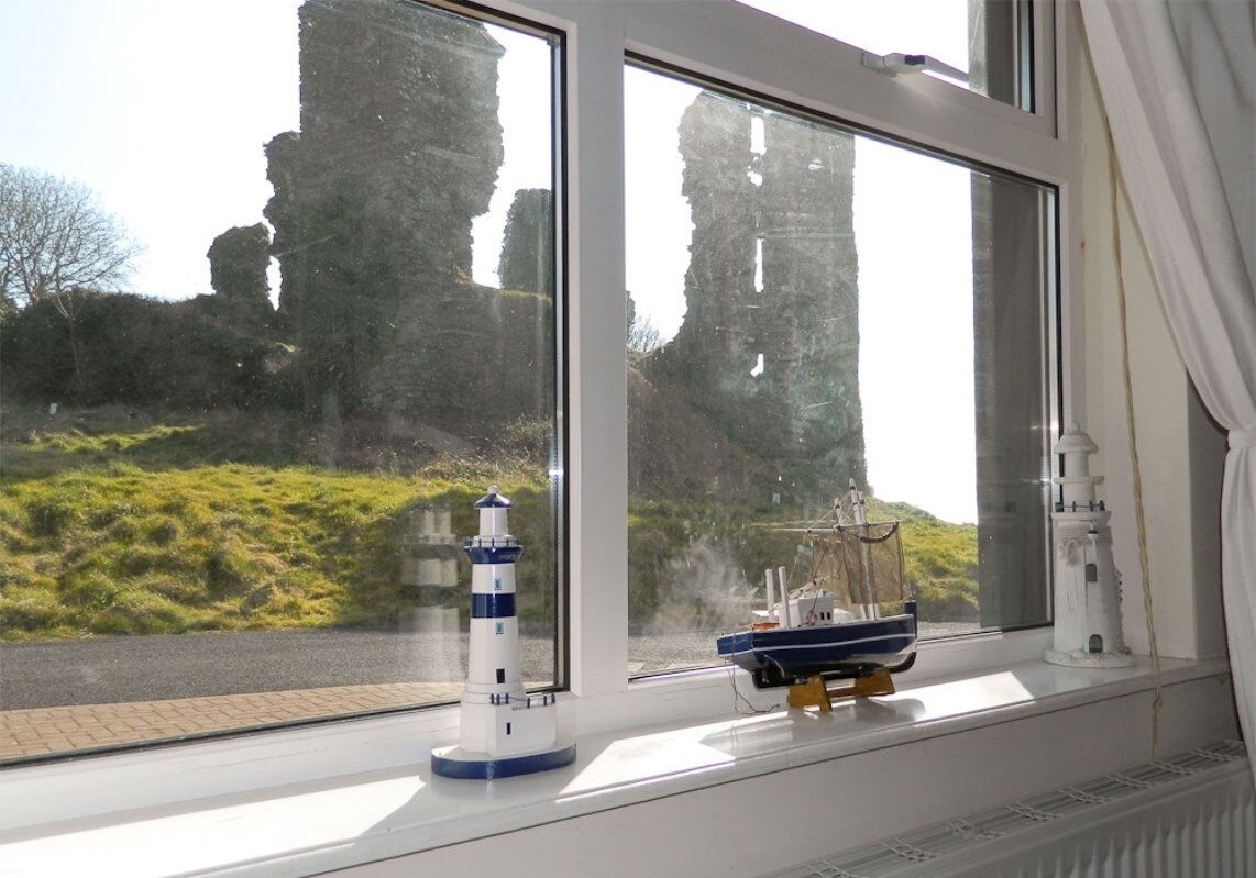 A window with a view of a lighthouse and a boat model on a windowsill.