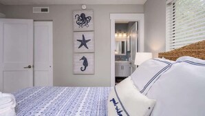 Een slaapkamer met een bed, een deur en wanddecoratie met zeedieren.