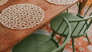 A wooden dining table with four green chairs and a woven placemat. - 2BD-3BA-3BEDS in the PERFECT location in Ocean Springs! Britt's Creek Condo (Ocean Springs)