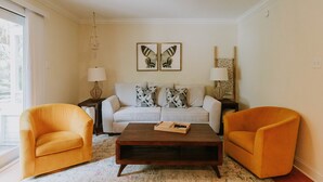 A living room with a sofa, two armchairs, a coffee table, and two butterfly wall art pieces. - 2BD-3BA-3BEDS in the PERFECT location in Ocean Springs! Britt's Creek Condo (Ocean Springs)