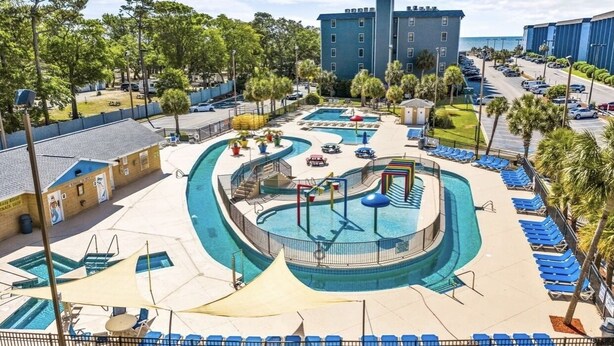 A pool area with multiple swimming pools, lounge chairs, and a playground. - NEW! Ocean-Front Resort, Steps From Beach, 6 pools and Lazy River (Myrtle Beach)