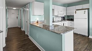 A modern kitchen with white cabinets, a granite countertop, and a built-in refrigerator. - NEW! Ocean-Front Resort, Steps From Beach, 6 pools and Lazy River (Myrtle Beach)