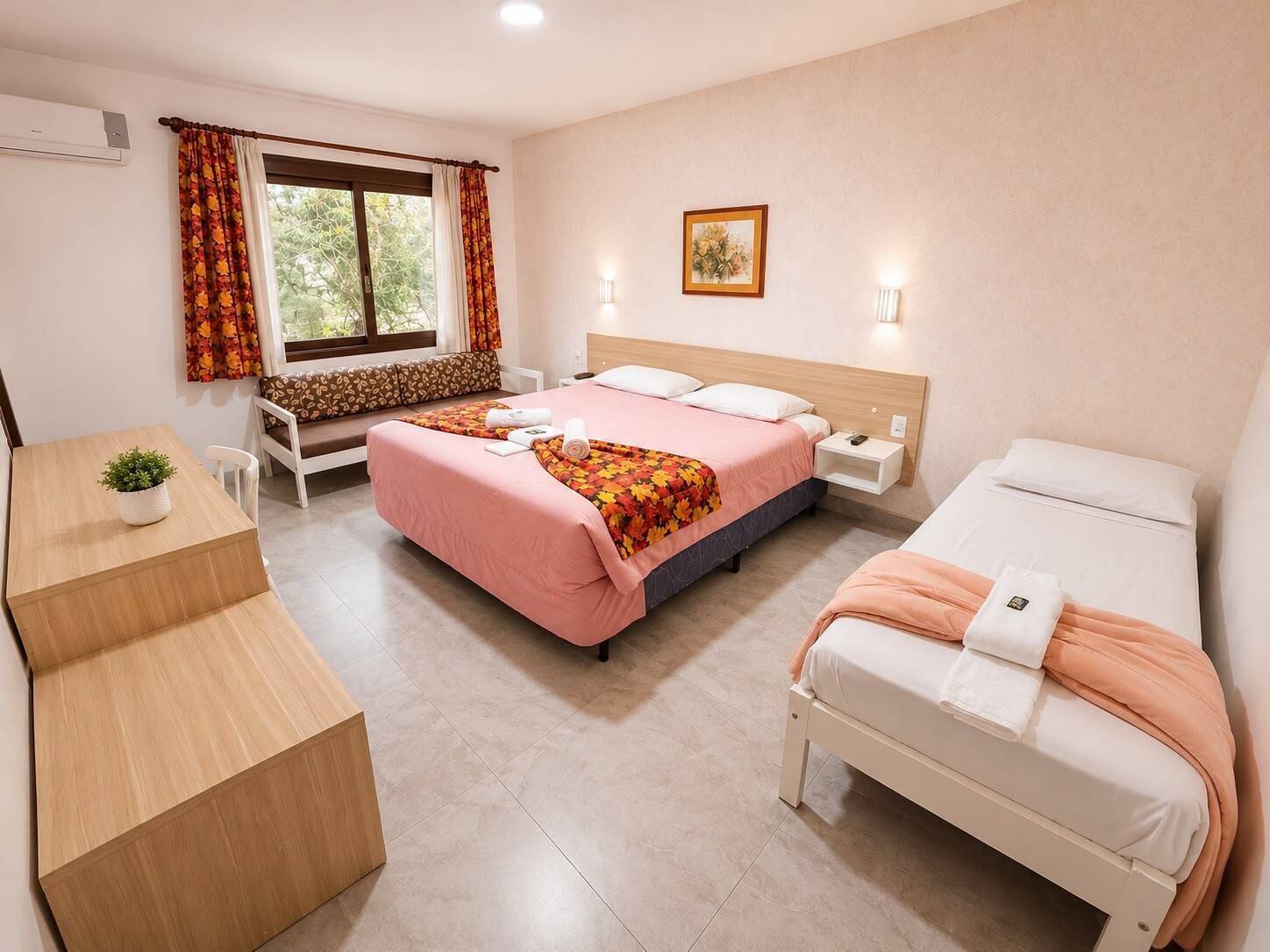 A hotel room with a bed, a sofa bed, a desk, and a window with curtains.