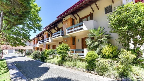 A hotel with a paved entrance, multiple balconies, and lush greenery. - Hotel Alpenhof (Gramado)