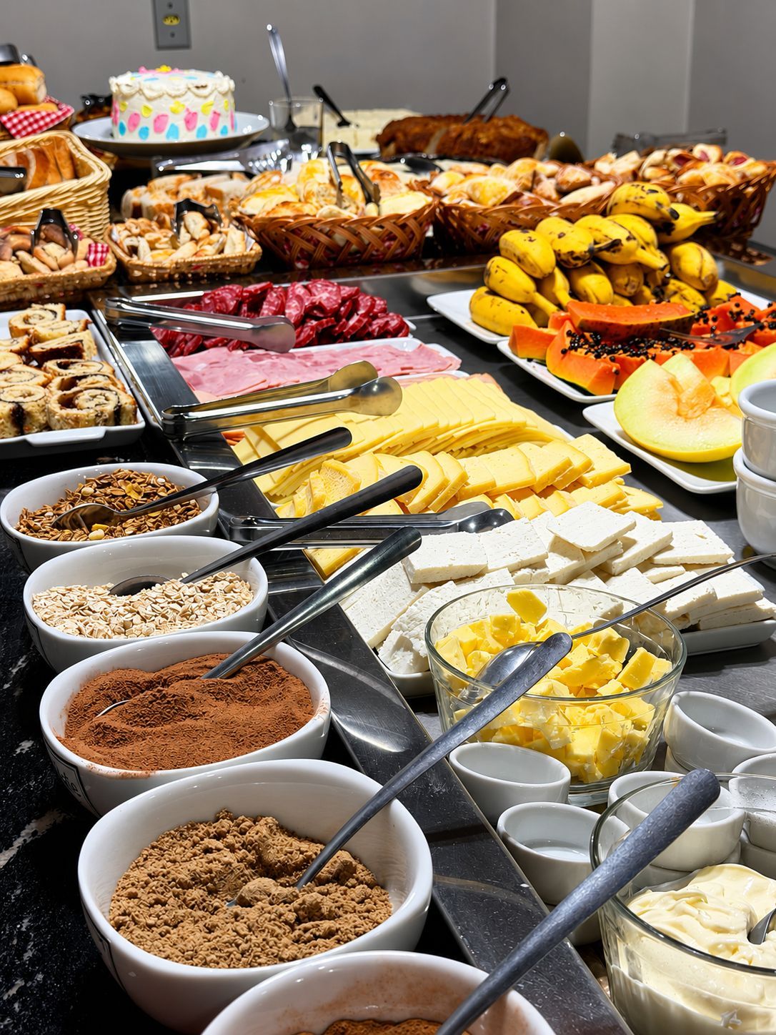 A buffet with various food items including meats, cheeses, fruits, and desserts.