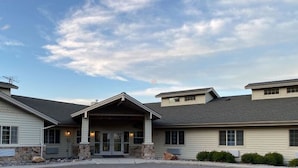 A building with a covered entrance, multiple windows, and a stone foundation.