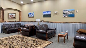 A hotel lobby with leather sofas, a patterned rug, and wall-mounted artwork.
