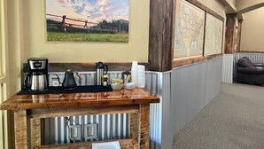 A hotel reception area with a wooden counter, coffee maker, kettle, and a map on the wall.