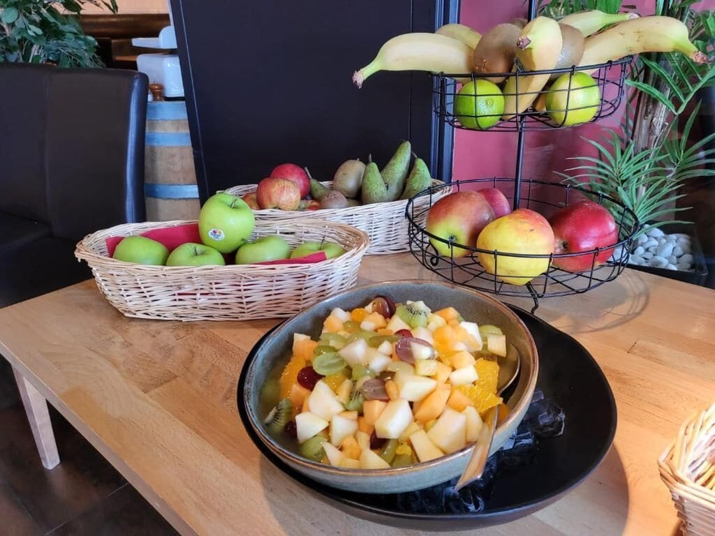 A table with fruit baskets and a bowl of mixed fruits.