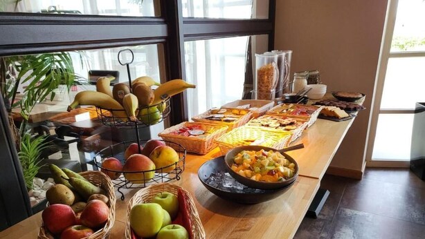 Una mesa de buffet con diversas frutas y platos, incluyendo manzanas, plátanos y un tazón de frutas mixtas.