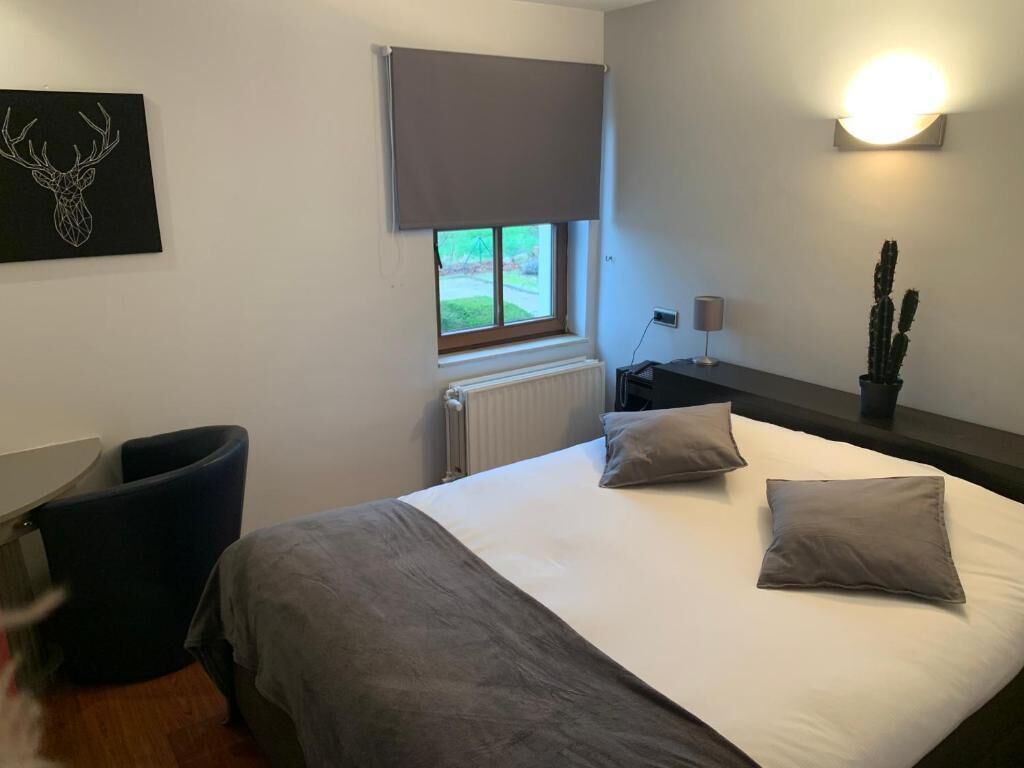 Une chambre à coucher avec un lit, une fenêtre donnant sur un beau paysage, un radiateur, un bureau et une chaise.