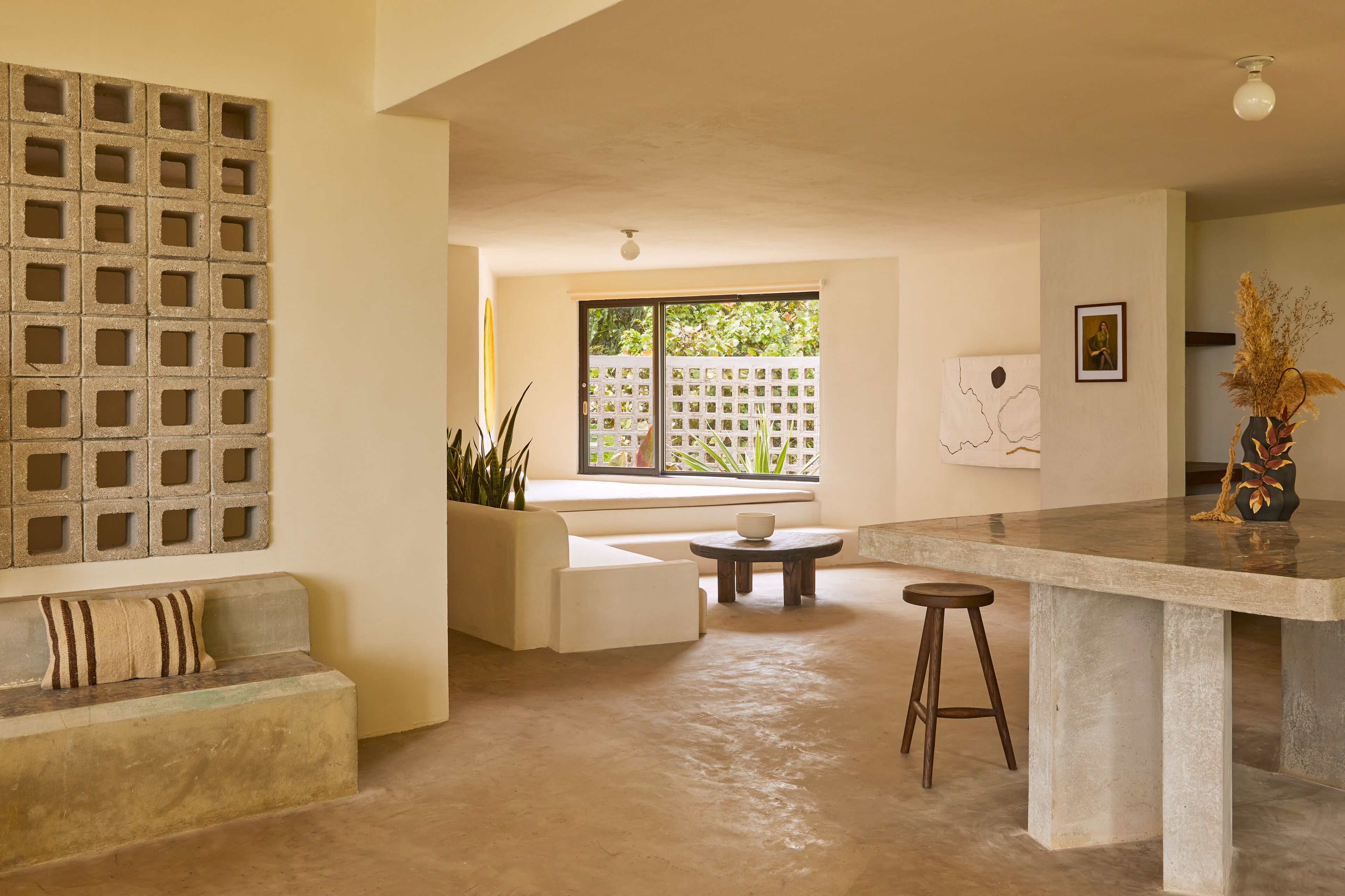 A modern interior with a concrete bench, a small round table, and a bar area.