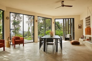 Une pièce spacieuse avec une grande table à manger, plusieurs chaises et un ventilateur de plafond.