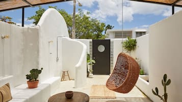 Relax in this open-plan living space with a curved wicker chair, round table, and comfortable sofa.