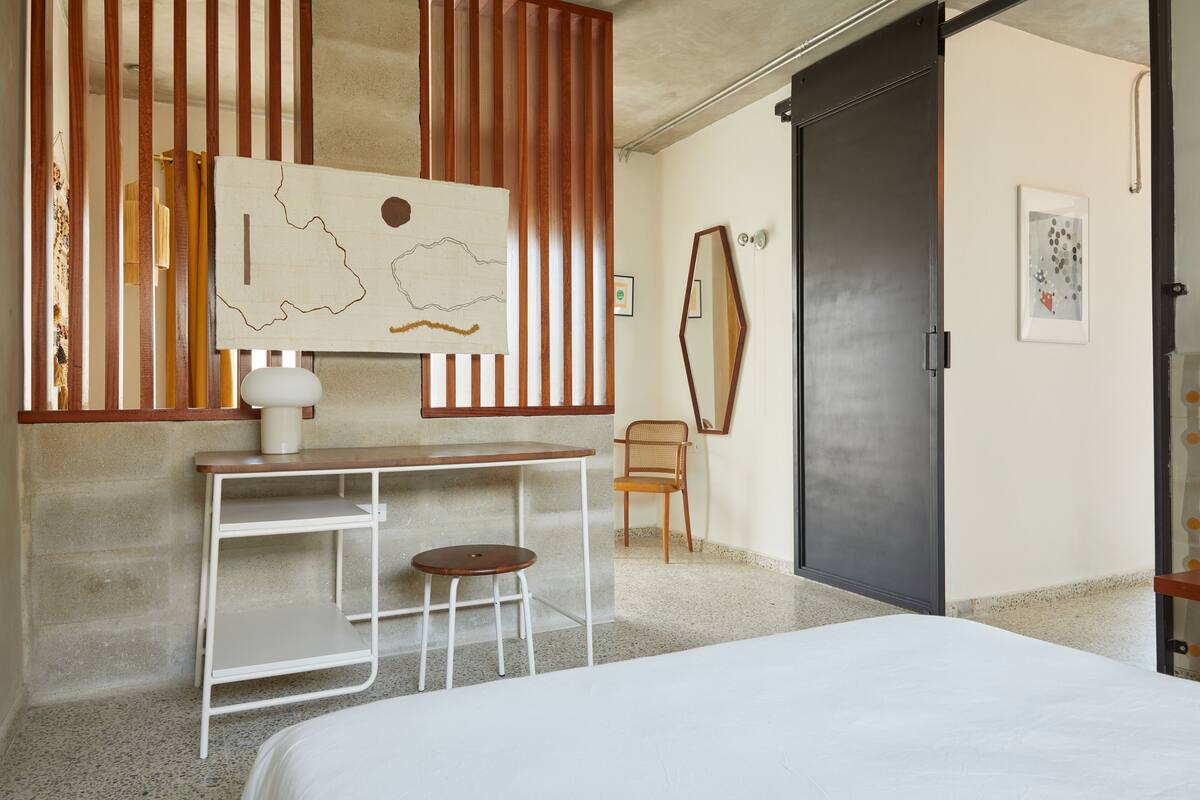 Une chambre à coucher avec un lit, un bureau et une chaise, une carte accrochée au mur et une porte.