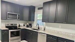 Una cocina moderna con armarios oscuros, electrodomésticos de acero inoxidable y encimeras de granito.